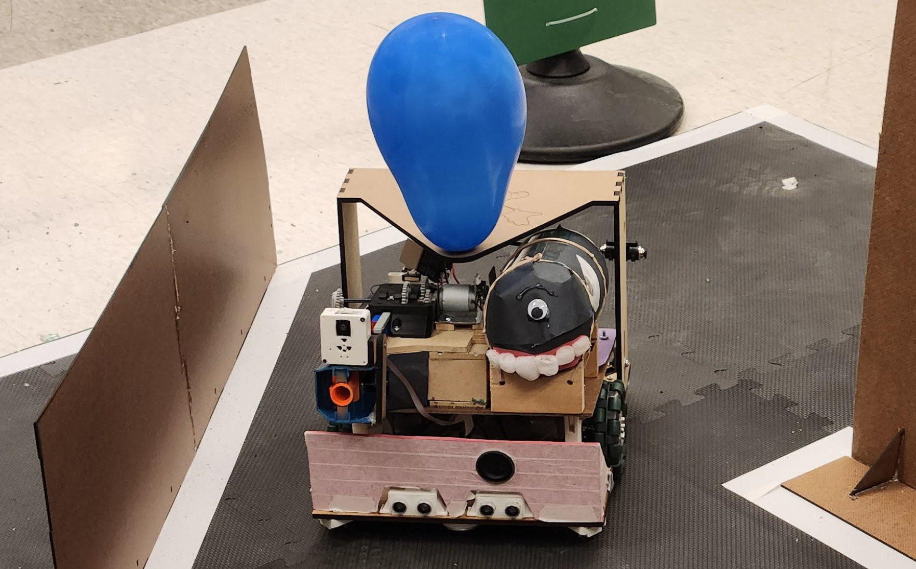 a robot in a competition arena. It has a balloon attached to its top.